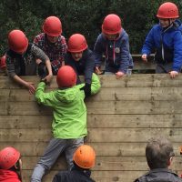 Young people help each other to scale a wall