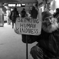 Man holding a sign reading "Seeking human kindness"
