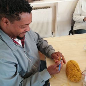 A man sitting at a table crocheting