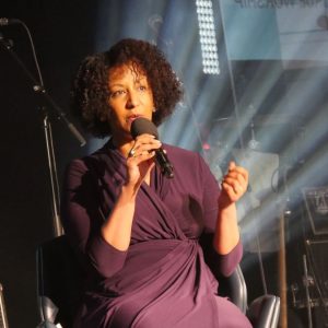Helen Berhane seated on a stage with a microphone