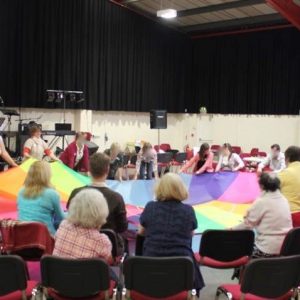 People sat around a rainbow parachute opened out at the MIX church gathering
