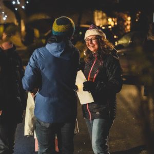 Two women speaking outside, one wearing a Santa hat
